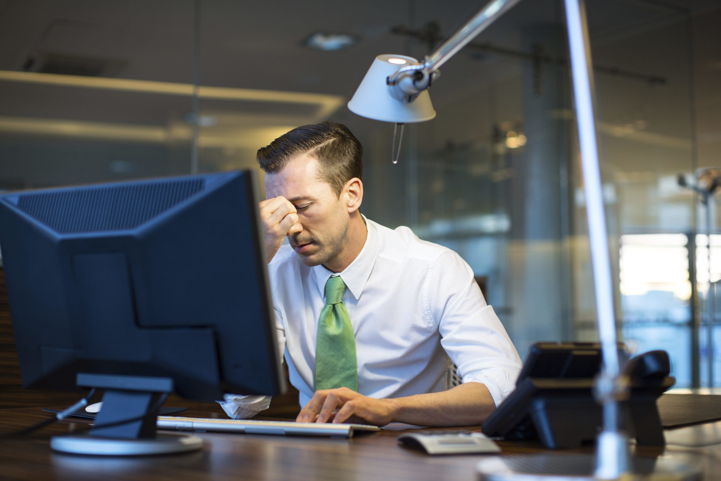 Business man at desk with his head in his hand